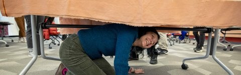 Mira Azram, an innovation instigator in the Academy for Innovation & Entrepreneurship at the University of Maryland, peers out from under a table during a recent improv workshop designed to help instructors bring more playfulness and creativity into their classrooms.