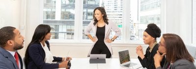 People sitting at a conference table with one person standing up