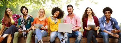 Racially and ethnically diverse university students sit together in row, smiling