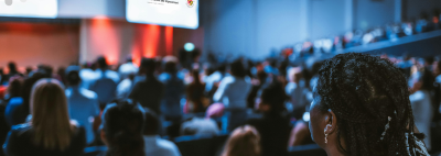 Woman in auditorium looking at screens with CEii logo