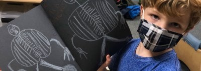Child holding his drawing of the skeleton