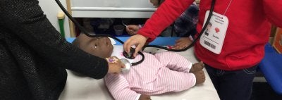 Preschool girls use stethoscopes with baby doll