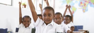 Children raise hands in international classroom 