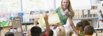 Teacher reads to students who are raising their hands