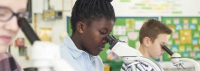 Girl looks into microscope in a classroom