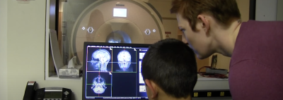 An experimenter and a child looking at a brain scan