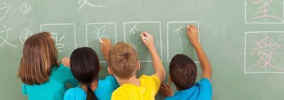 Children write in world languages on a chalkboard