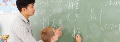 Boy and teacher write on a chalkboard