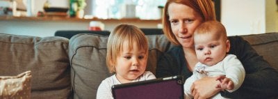 A mom and two children looking at an iPad. 