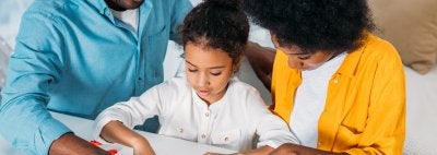 African American Mom and Dad doing math work with daughter