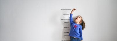 girl measuring her height against wall stock photo