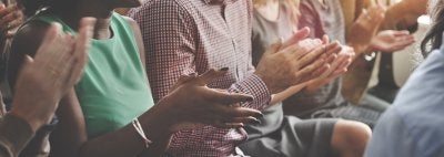 Stock photo of people clapping while sitting down