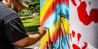 Graduate student Samir Razzak paints an electrical box as part of a community-based art partnership with the Lakeland community of College Park and Clinical Associate Professor Margaret Walker.