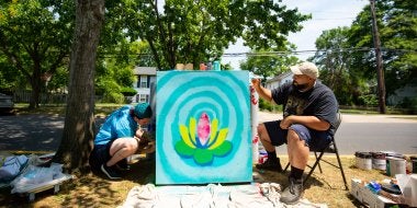 College of Education graduate students paint an electrical box in the Lakeland community of College Park as part of a community-based art project with Lakeland residents and Clinical Associate Professor Margaret Walker.