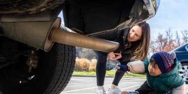 A child points to the tail pipe during a demonstration for their car study.