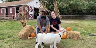 TerpsEXCEED Student and Peer Mentor at Campus Farm petting a sheep