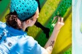 A College of Education graduate student paints an electric box in the Lakeland community of College Park as part of  a community-based art project with Lakeland residents and Clinical Associate Professor Margaret Walker.