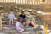 Children sit on rock steps on the playground.