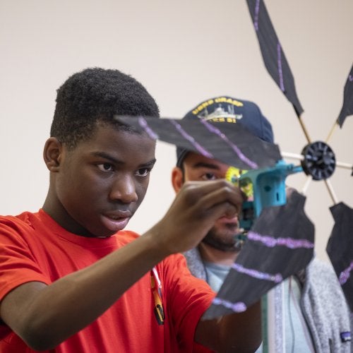 A student adjusts his team's small-scale wind turbine at the 2023 Maryland Regional KidWind Challenge.