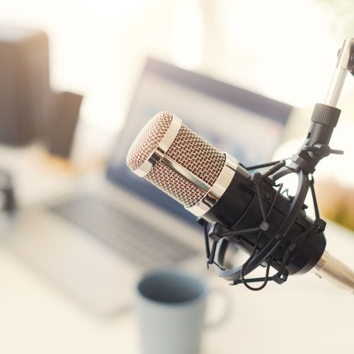 A podcast setup including a microphone and laptop. Photo by iStock/demaerre