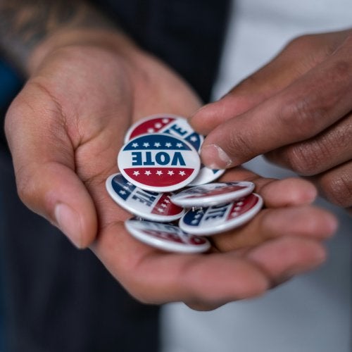 Hands holding buttons that say "VOTE"