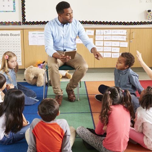 A teacher engages with a group of elementary students.