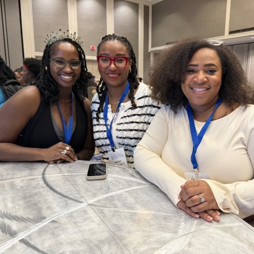 The three UMD College of Education Holmes Scholars sit together at a table at the Holmes Scholars Preconference to the American Association of Colleges for Teacher Education Annual Meeting.