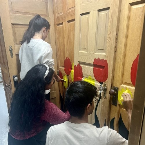 Students in the community-based art course HNUH278Q paint the doors that make up the main structure of the community art project.