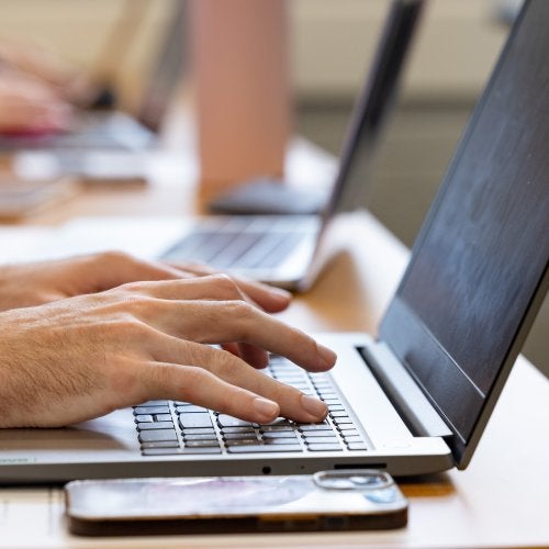 A close up of a student's hands typing on a laptop in a Benjamin Building classroom.