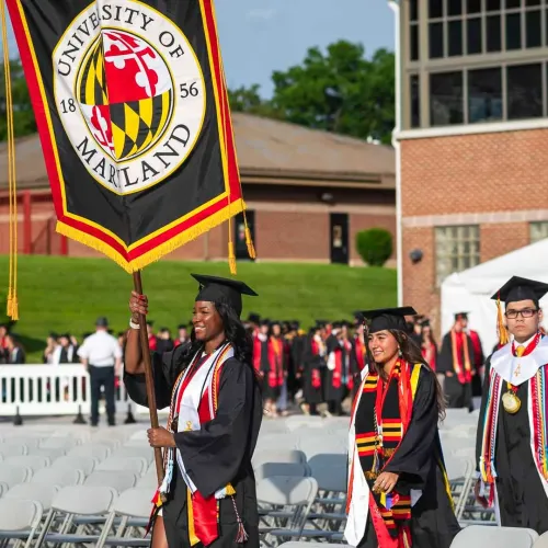 Senior marshals march and carry banners at UMD's main Commencement ceremony.