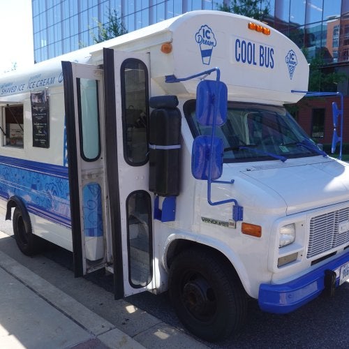 Carol Pisciotta '96 runs her ice cream and shaved ice business out of a school bus converted into an ice cream truck. The bus is painted blue and white, with the words "COOL BUS" on the front.