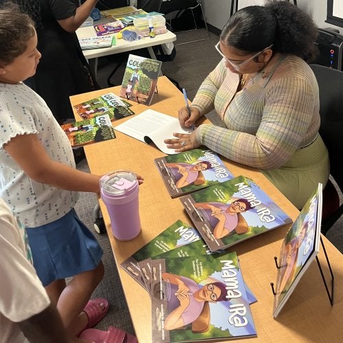 An author signs a book for a student in the Summer Reading Program