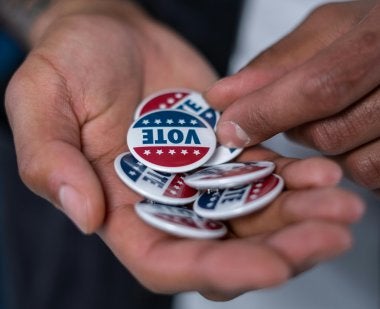 Hands holding buttons that say "VOTE"
