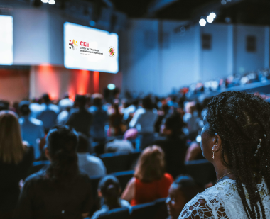 Woman in auditorium looking at screens with CEii logo
