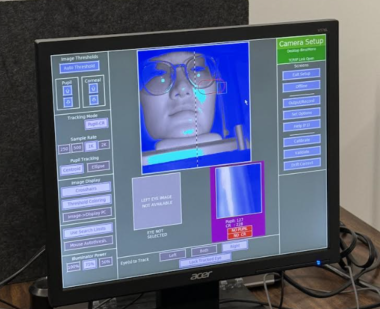 A screen used in eye tracking research shows a person's face as they read and listen to text