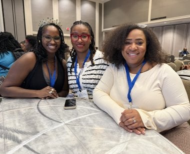 The three UMD College of Education Holmes Scholars sit together at a table at the Holmes Scholars Preconference to the American Association of Colleges for Teacher Education Annual Meeting.