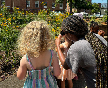 A student intern observes plants with children