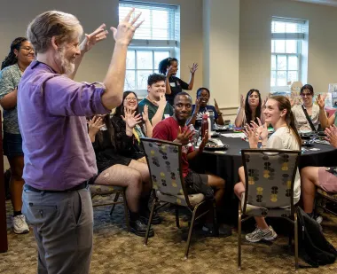 Michael Dunham, lecturer and program director for UMD's American Sign Language minor, applauds with students at a signing dinner, where everyone communicated solely by using ASL.