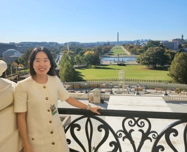 Jeongeun Kim, associate professor of higher education, stands at a Capitol Building balcony with the Washington Monument behind her during her AERA Congressional Fellowship.