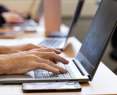 A close up of a student's hands typing on a laptop in a Benjamin Building classroom.