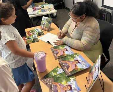 An author signs a book for a student in the Summer Reading Program