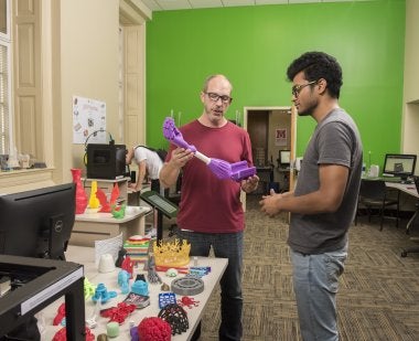 Preston Tobery demonstrates a 3-D printed prosthetic in the MakerSpace lab at McKeldin