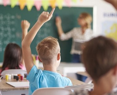 kids raising hands in classroom