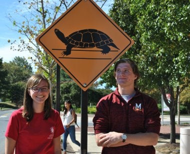 two student ambassadors in front of turtle crossing sign