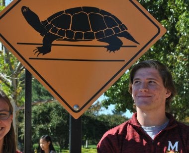two student ambassadors in front of a turtle crossing sign