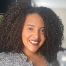 Headshot of a smiling, Afro-Latina, female-presenting woman with mid-length curly hair