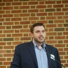 Chris Piper, a policy researcher at the Partnership for Public Service, speaks at a podium at the "Who Has the Power? The Constitution and Our Role in Securing Democracy” event.