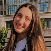 Amira Dacy with straight long brown hair and in a white shirt 