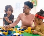 Teacher and two children play with blocks