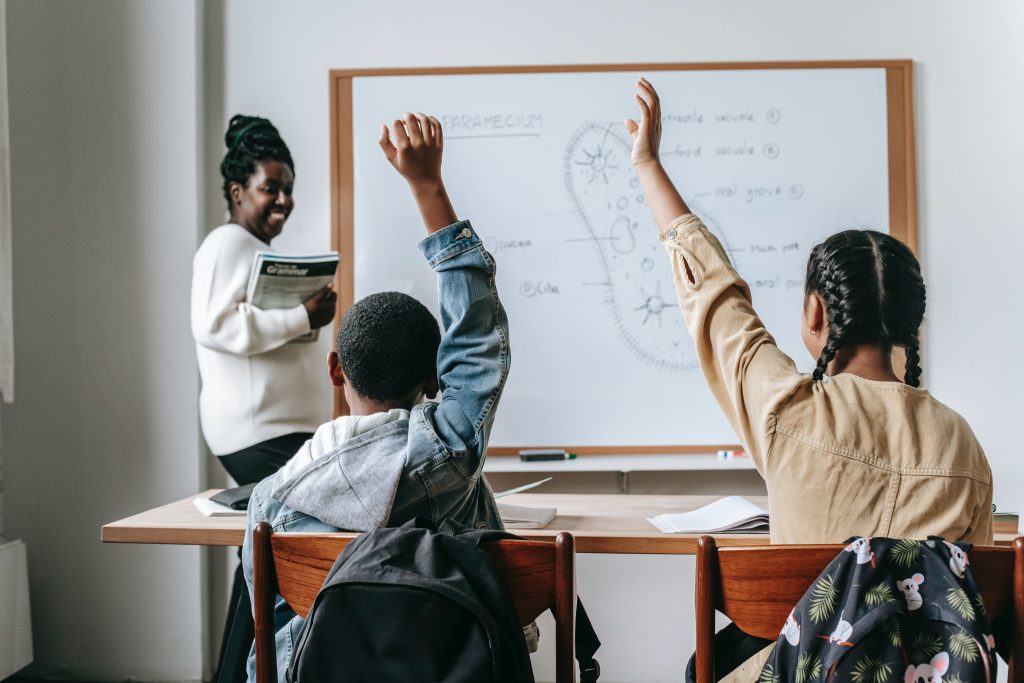 Teacher with students raising hands in classroom